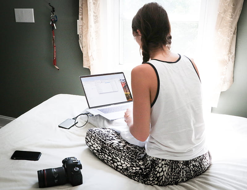 woman in white tank top sitting on bed in front of laptop computer, HD wallpaper