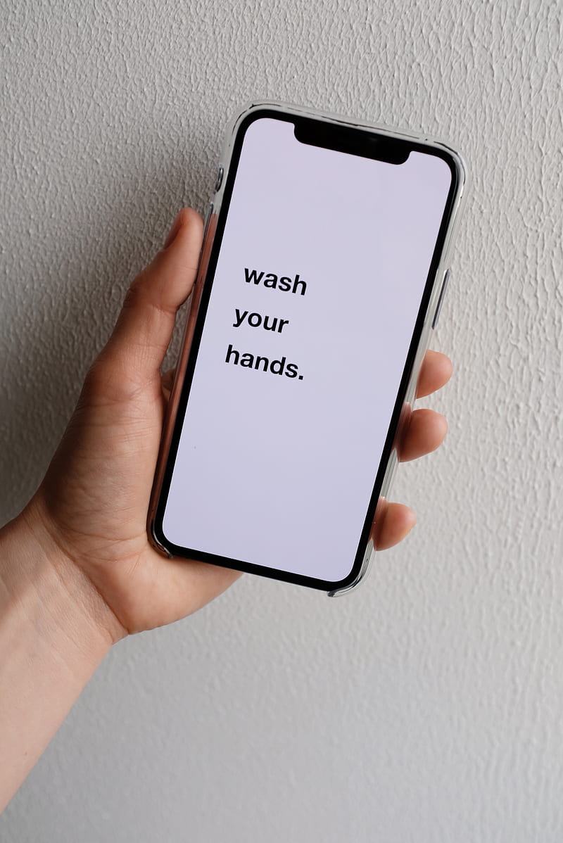 Crop anonymous person demonstrating modern cellphone screen with WASH YOUR HANDS inscription on white background with uneven surface in daylight during COVID 19 pandemic, HD phone wallpaper