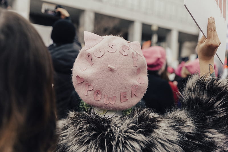 selective focus graphy of person wearing pink fleece Pussy Power cap raising right hand, HD wallpaper