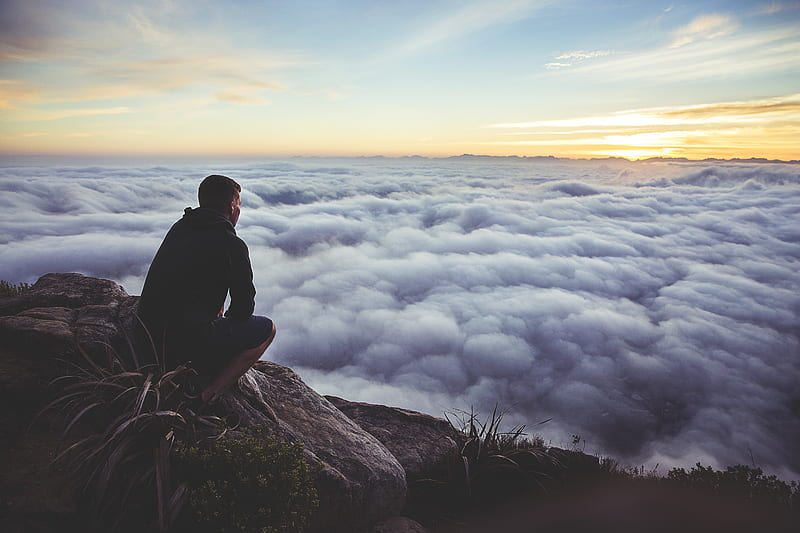 man sitting on gray rock while staring at white clouds, HD wallpaper