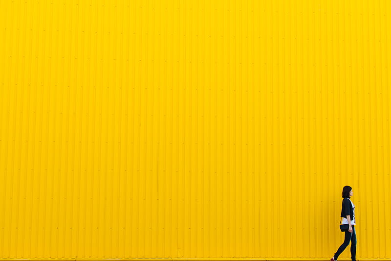 woman wearing black top standing near yellow wall, HD wallpaper