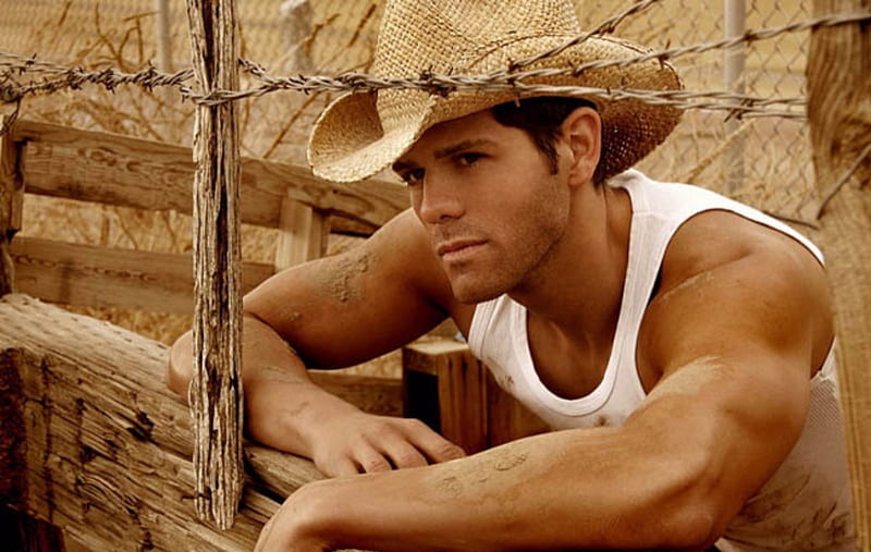 muscular man in a tank top working on a rural fence