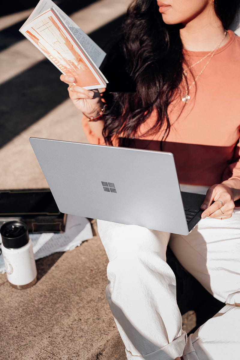 woman in orange shirt and white pants holding silver microsoft surface laptop computer, HD phone wallpaper