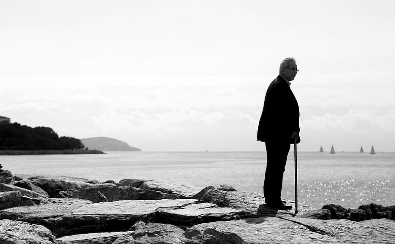 man in black coat standing on rocky shore, HD wallpaper