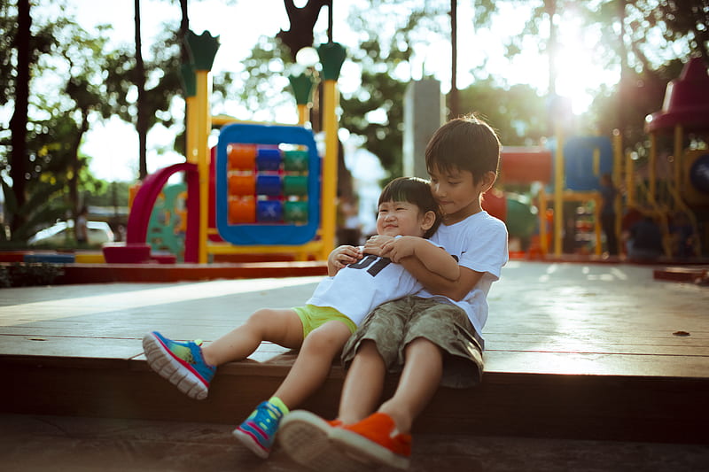 boy carrying child while sitting on gray concrete platform, HD wallpaper