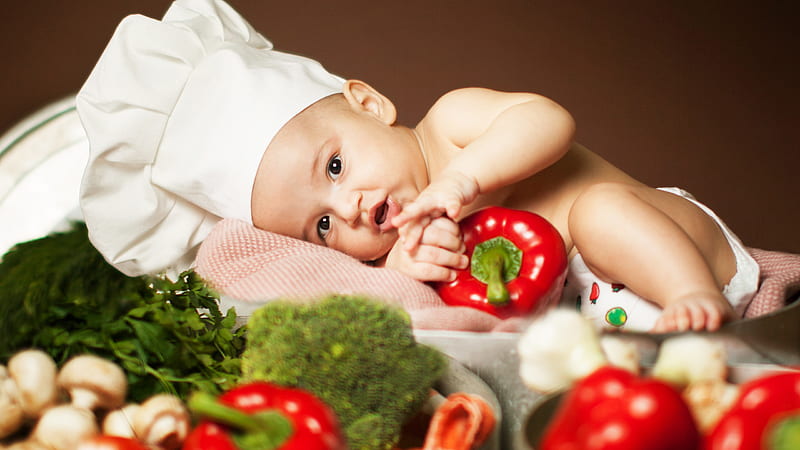 cute baby boy is lying on orange towel wearing chef cap having red capsicum in hand cute, HD wallpaper