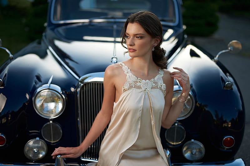 A model poses for a photo with a vintage car