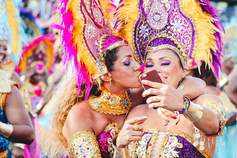 Two women Carnival dancers pose for a selfie as one kisses other on the cheek., HD wallpaper