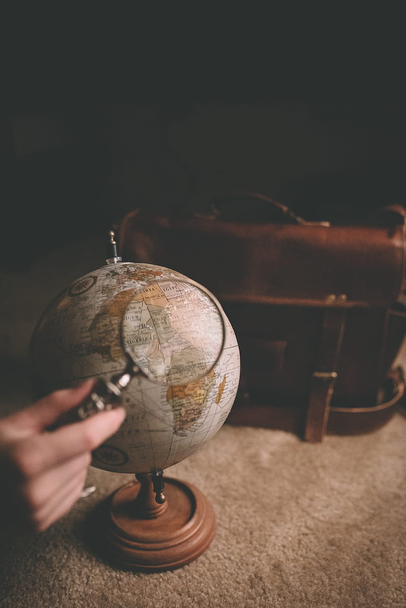 person holding magnifying glass near desk globe, HD phone wallpaper