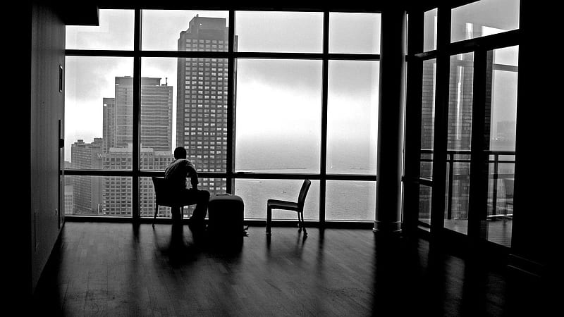 Man sitting beside glass window near high rise building photo