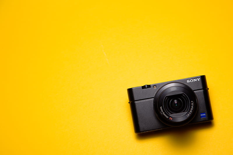 black Sony point-and-shoot camera on yellow surface, HD wallpaper