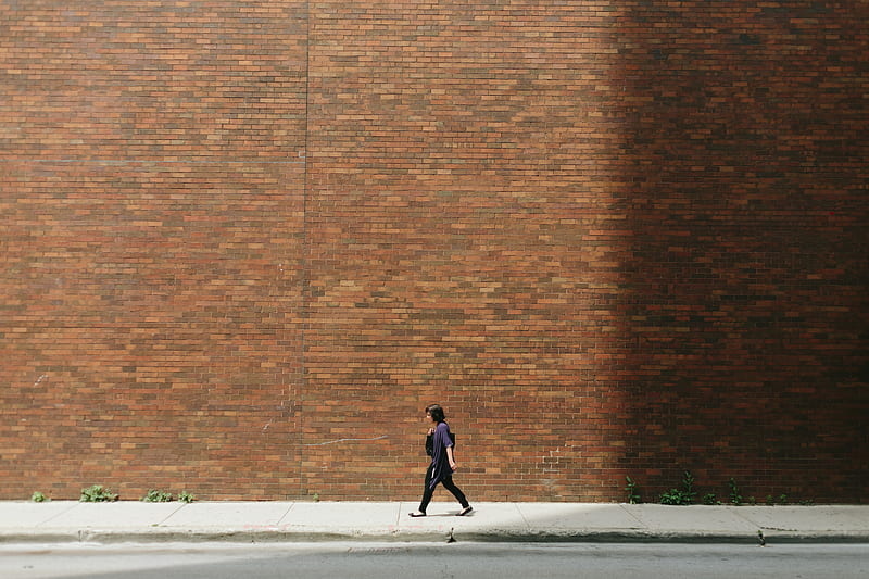 woman in black shirt walking on sidewalk near brown concrete wall partition, HD wallpaper