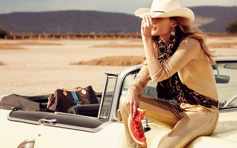 Cow Girl Edita Vilkeviciute, posing on the hood of a convertable, water melon, cowboy hat, brunette, desert scene, HD wallpaper