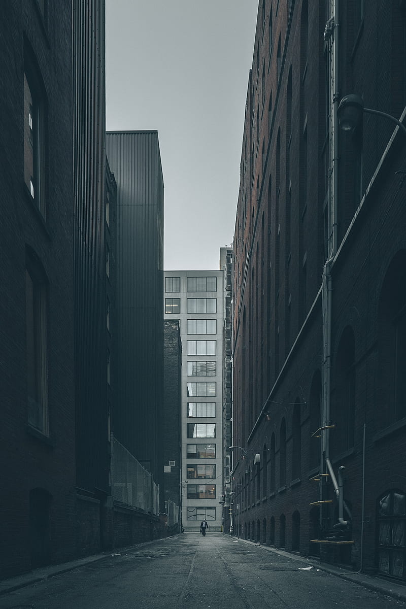 man walking in the middle of city buildings under gray clouds, HD phone wallpaper