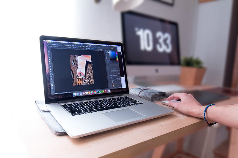person using MacBook Pro on brown wooden desk, HD wallpaper