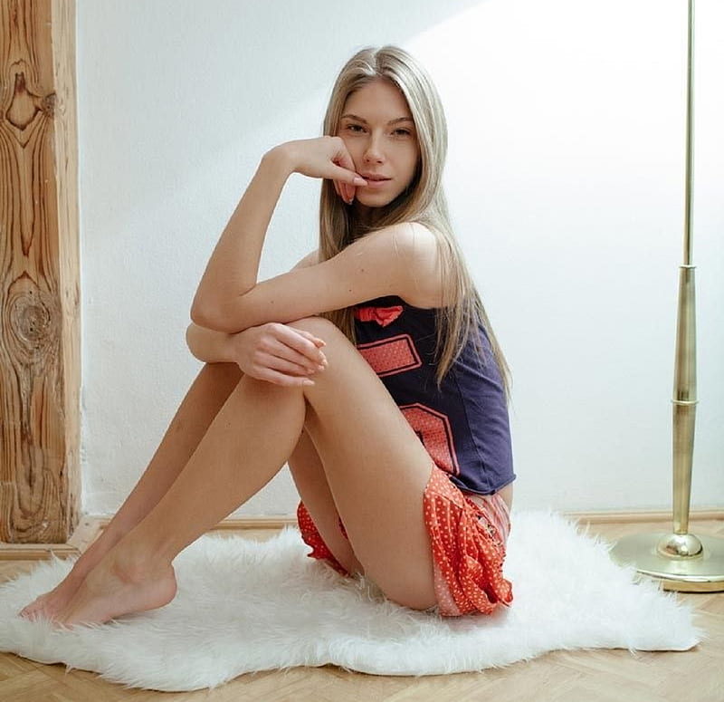 Anjelica Ebbi, red skirt, blue sports vest, sitting on white shaggy rug, polka dots, blonde, standard lamp, HD wallpaper
