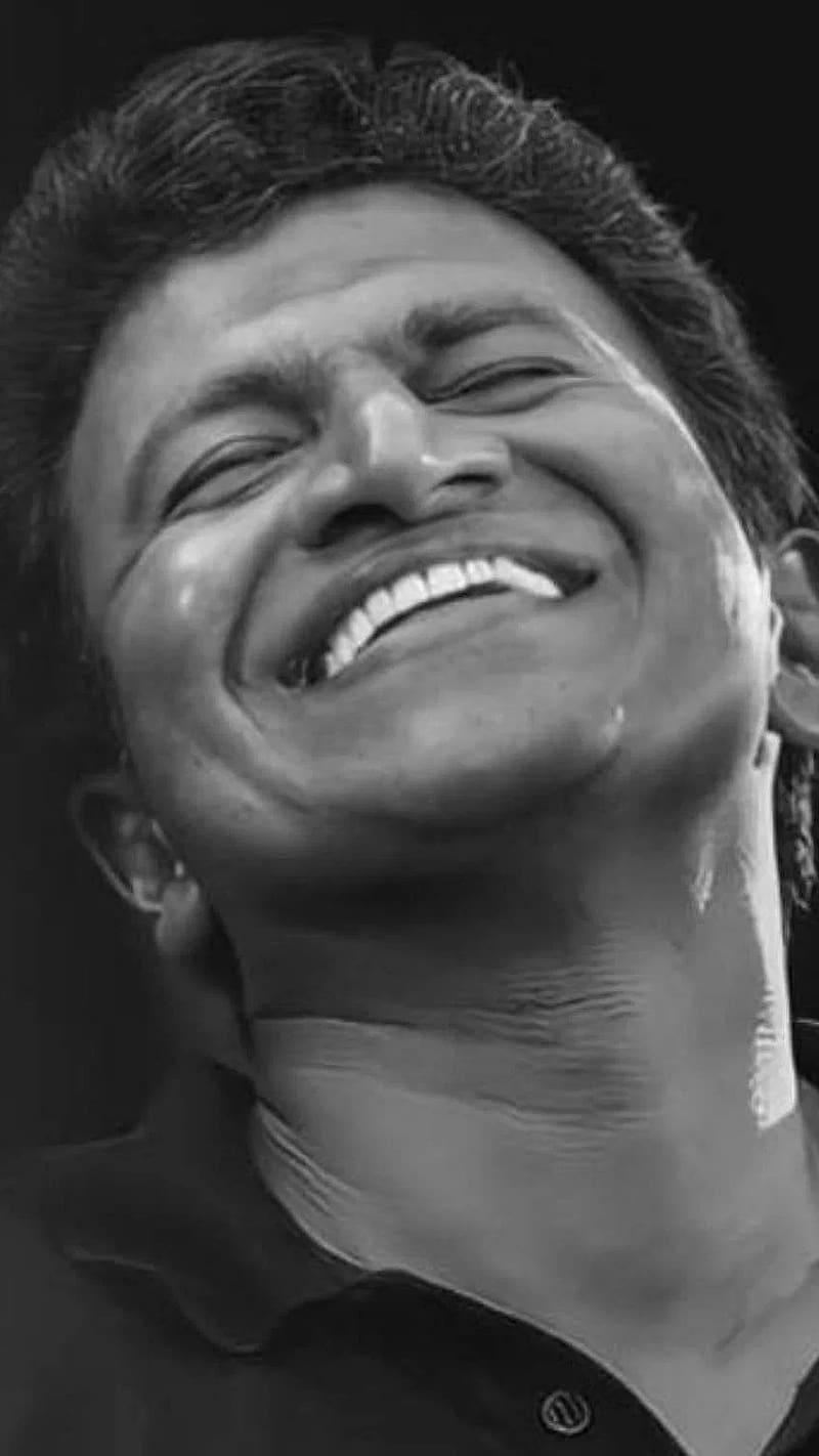 Smiley Puneeth Rajkumar Is Wearing White T-Shirt And Black Shirt Standing  In Colorful Lights Bokeh Background HD Puneeth Rajkumar Wallpapers | HD  Wallpapers | ID #92058