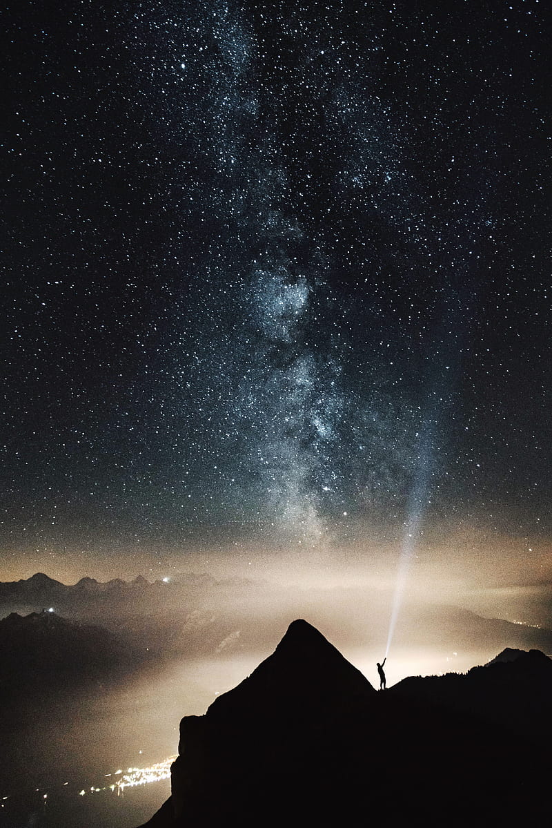 silhouette of person on top of mountain pointing flashlight on sky filled with stars at night time, HD phone wallpaper
