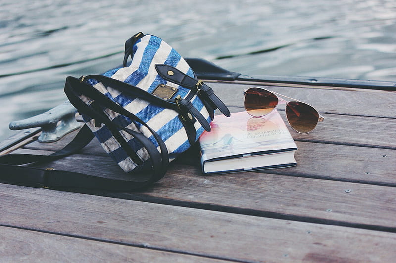 blue and white striped crossbody bag near book and sunglasses on sea dock during daytime, HD wallpaper