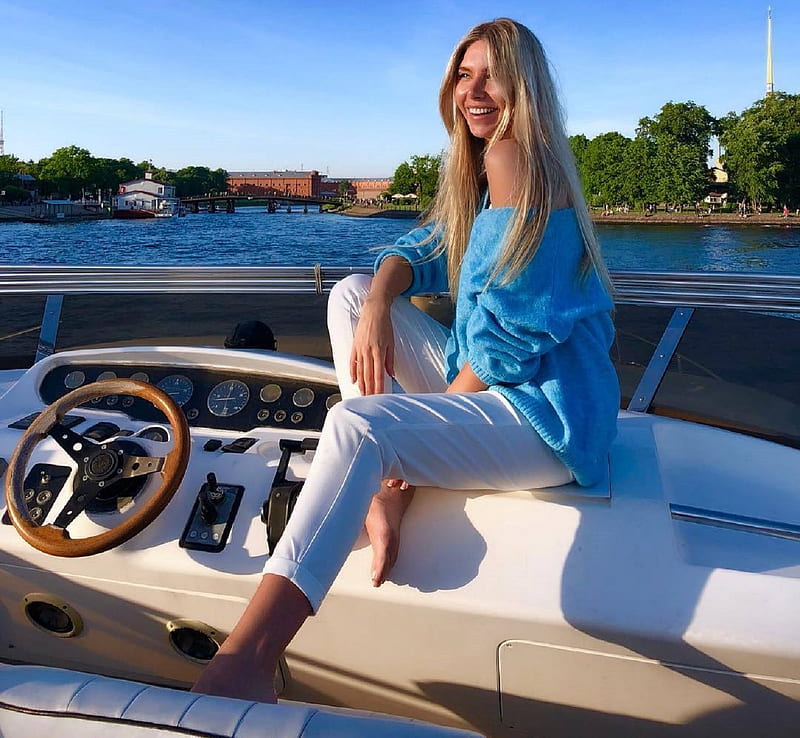 Anjelica Ebbi enjoying a boat ride, pale blue sweater, white capri pants, blonde, steering wheel, revealing left shoulder, coast, instrument panel, water, boat, sitting, HD wallpaper