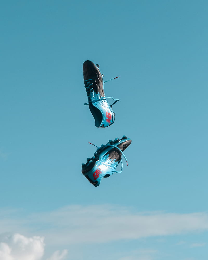 pair of blue-and-black New Balance cleats in the air under teal sky with white clouds, HD phone wallpaper