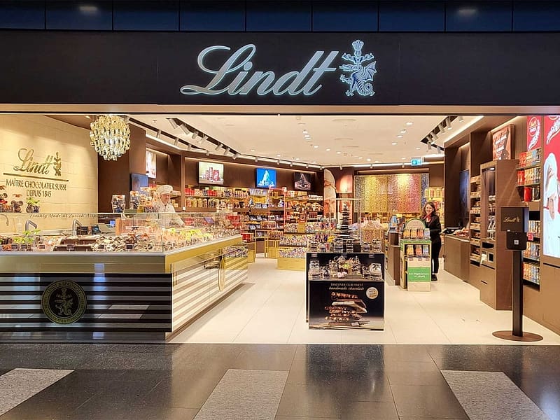 LINDT CHOCOLATE BOUTIQUE ZURICH AIRPORT, STORE ENTRANCE, BEAUTIFUL LAYOUT, MADE IN THE STORE, ASSISTANT BEHIND REGISTER, AISLES OF EVERY KIND, HD wallpaper