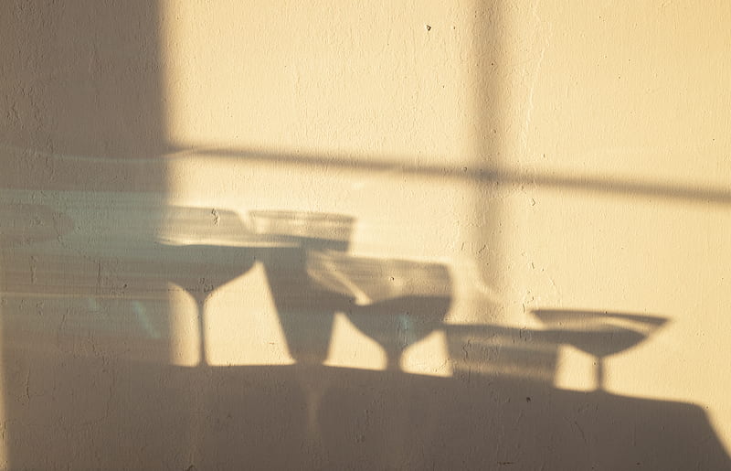 Shadows of different crystal glasses filled with drinks reflecting on white wall in sunlight, HD wallpaper