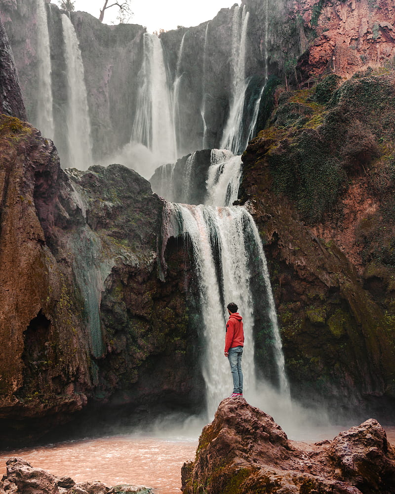 man wearingred pullover standing in front of waterfalls, HD phone wallpaper