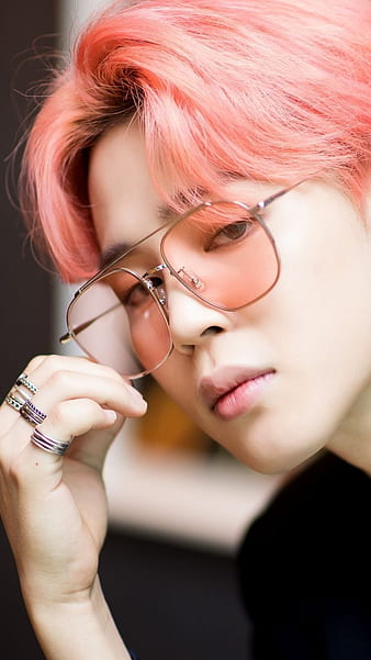 The singer wears a hot pink robe-like jacket and a fluffy pink boa. he has  dark brown, fluffy, wavy hair and he's wearing rose-colored, heart-shaped  glasses. he is tan on Craiyon