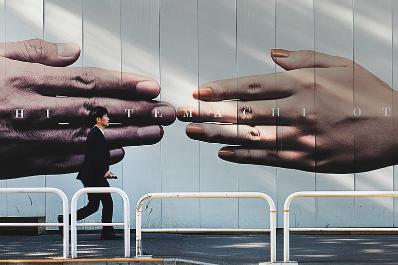 man walking on sidewalk beside hands mural, HD wallpaper