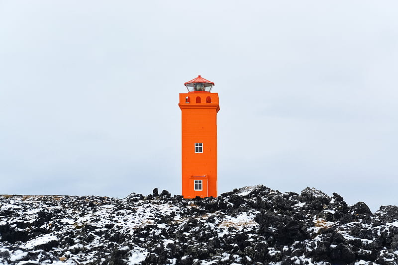 orange and white lighthouse on rocky ground under gray sky, HD wallpaper