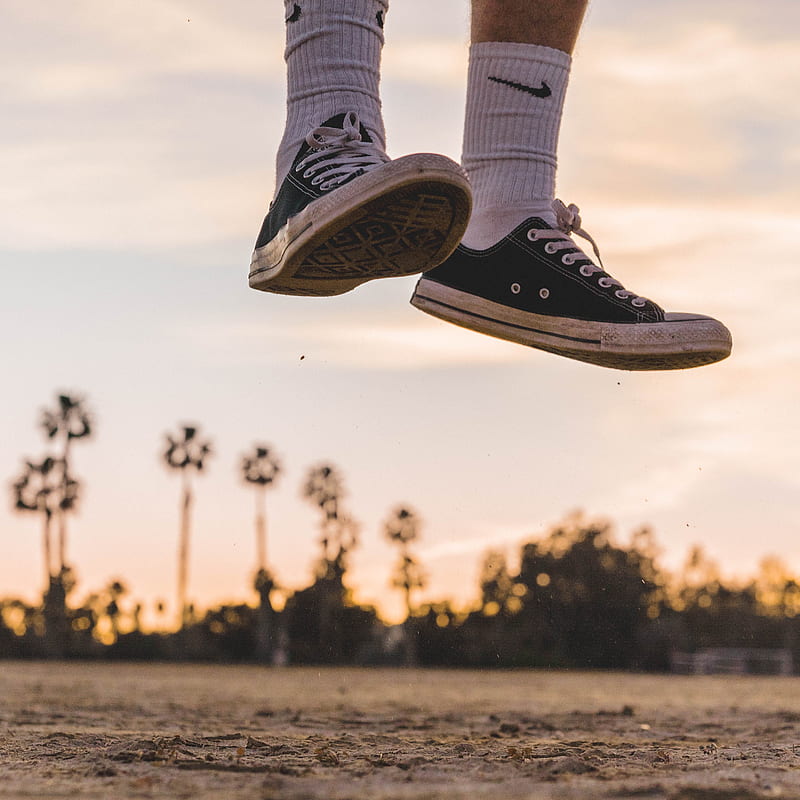 person wearing black low-top sneakers jumping high under white sky, HD phone wallpaper