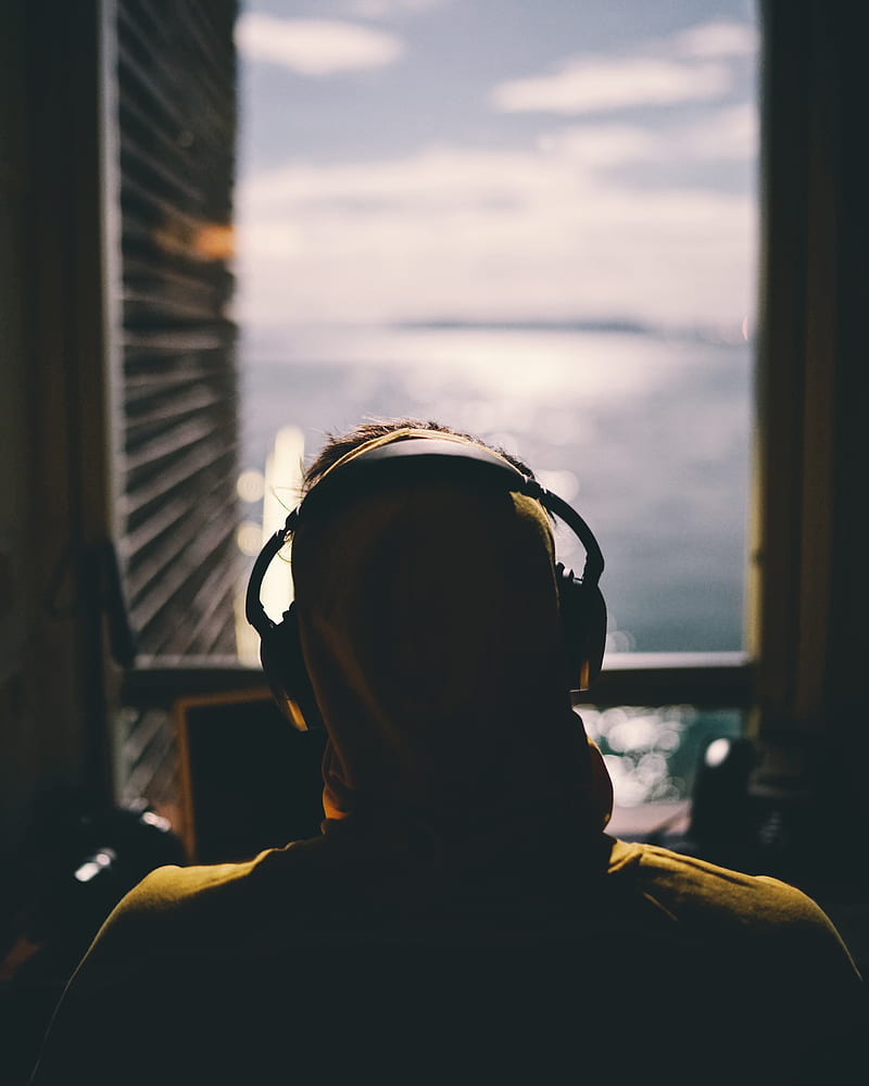 tilt-shift lens graphy of person wearing headphones facing body of water through window of a dark room, HD phone wallpaper