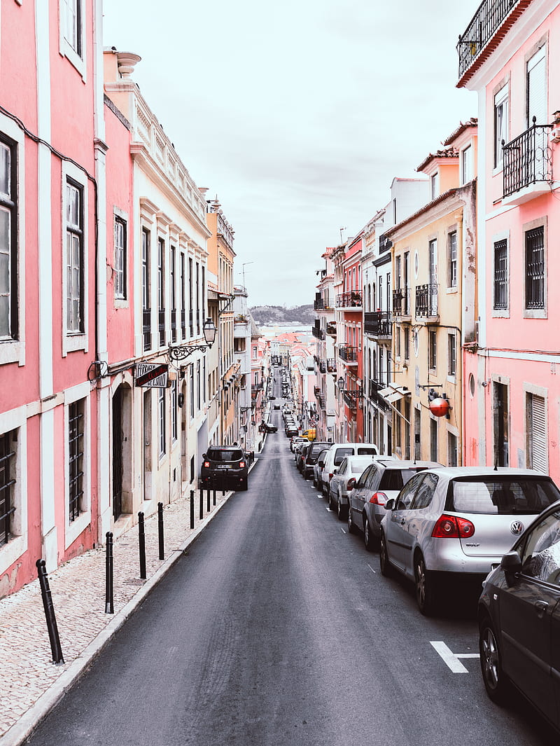 line of vehicles on the right side of a 2-way road in the middle of pink and yellow buildings during day, HD phone wallpaper