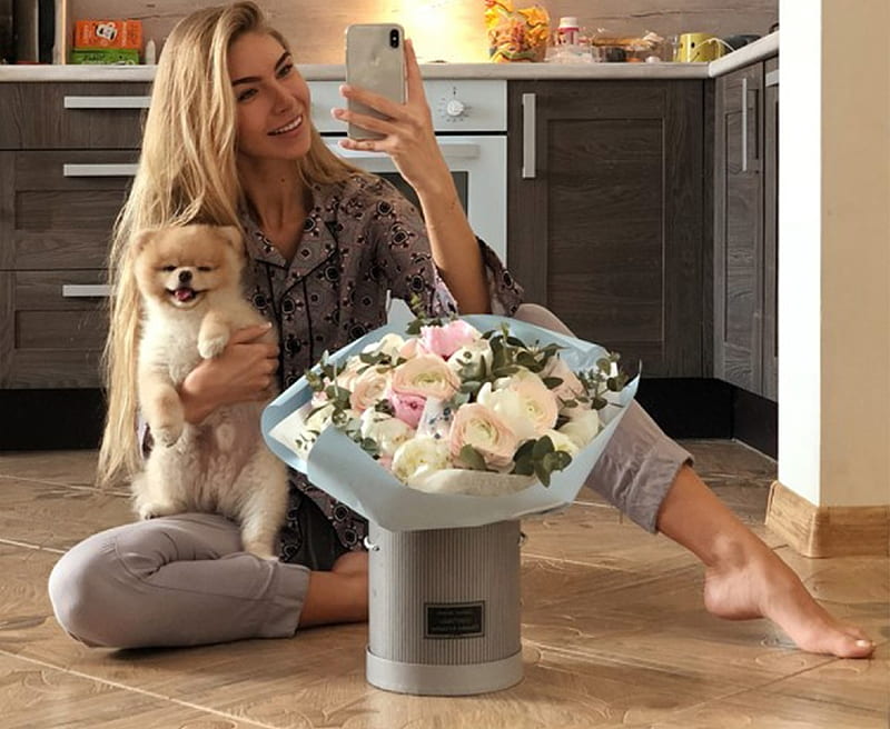 Anjelica Ebbi, cell phone, grey bucket, sitting on floor, blonde, flowers, kitchen, dog, patterned, grey pants, dark grey top, HD wallpaper