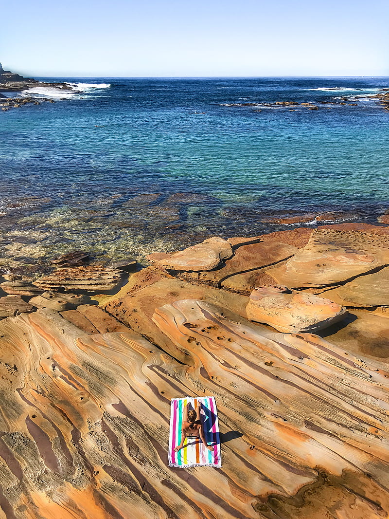 People Standing On Brown Rock Formation Near Body Of Water During