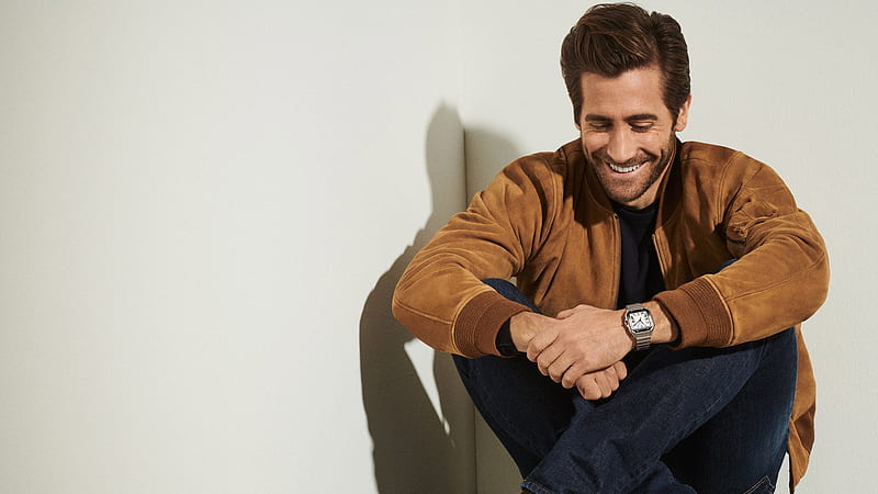 Smiley Jake Gyllenhaal Is Sitting On Floor Looking Down Wearing Brown Jacket And Jeans Celebrities, HD wallpaper