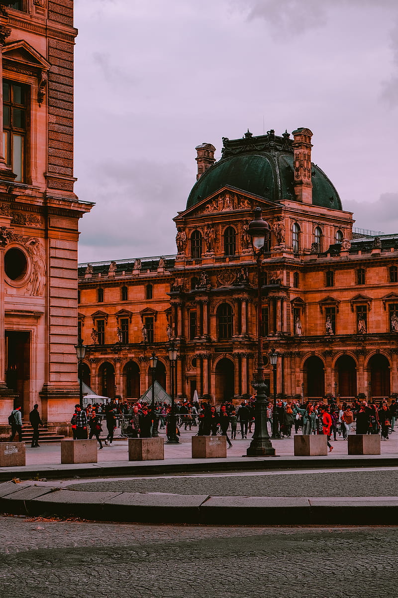 People walking near Louvre Museum in Paris, France under white skies ...
