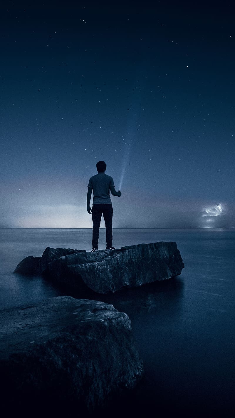 Alone Boy, Standing On The Rock, standing, rock, torch, stars, water, HD phone wallpaper