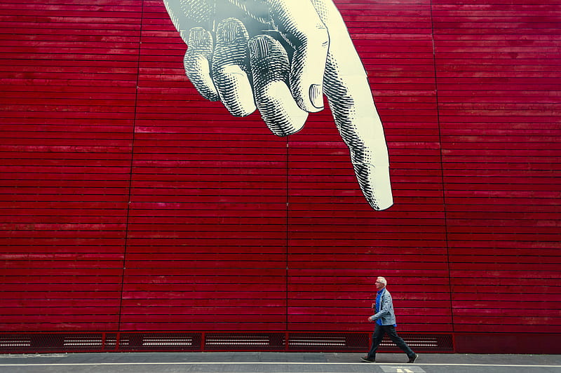 A person walking by a wall painting of a realistic hand with its index finger pointing down., HD wallpaper