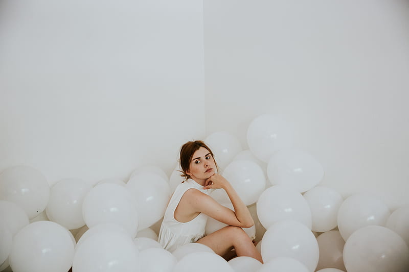 woman wearing white sleeveless tops sitting on floor surrounded by white balloons inside white painted room, HD wallpaper