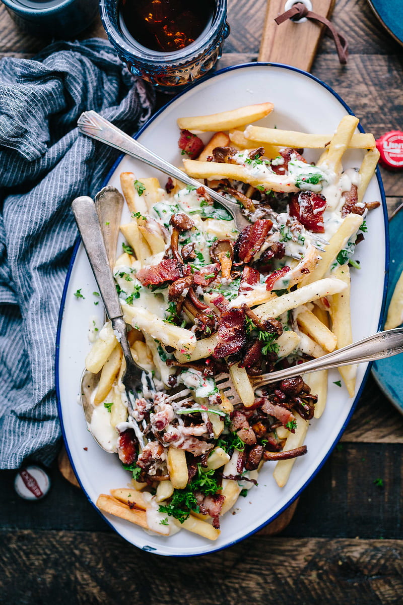 bacon strips and melted cheese topped fries on oval white and blue platter with gray stainless steel forks, HD phone wallpaper