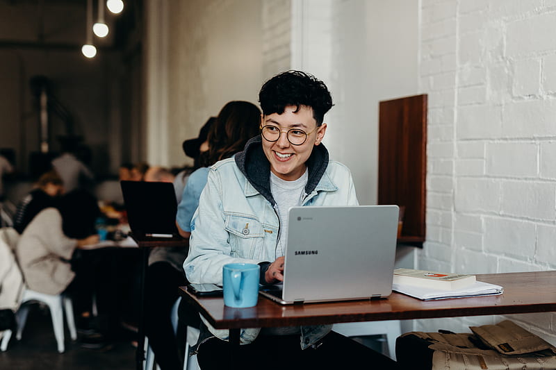 smiling man sitting and using Samsung laptop near people, HD wallpaper
