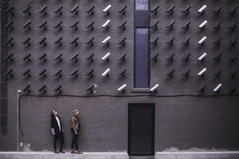 two women facing security camera above mounted on structure, HD wallpaper