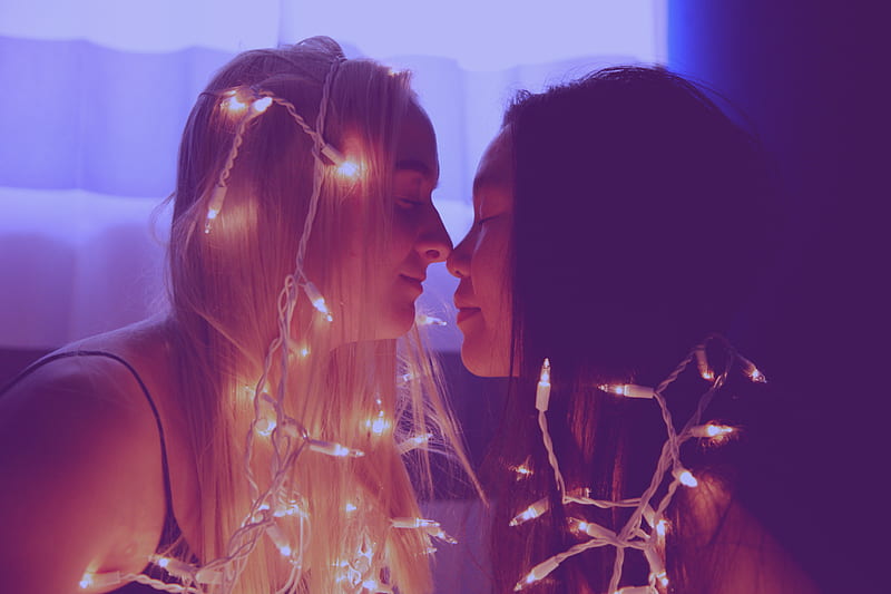 two woman facing each other with string lights, HD wallpaper