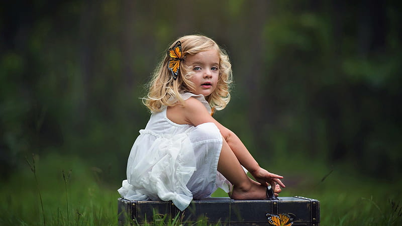 Cute Little Girl Is Sitting On Suitcase Wearing White Dress With Butterfly Clip In Head In Green Blur Background Cute, HD wallpaper