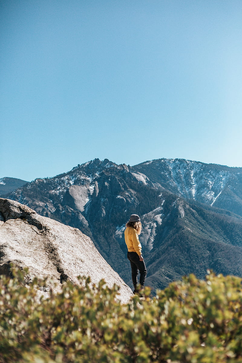 woman in yellow sweatshirt and black pants standing near cliff under blue sky during daytime, HD phone wallpaper