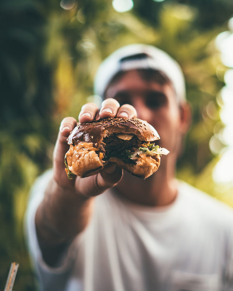 selective focus graphy of man holding eaten burger, HD phone wallpaper