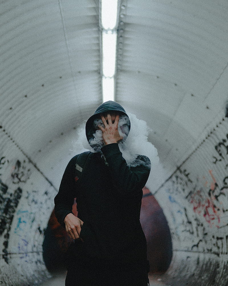 man standing wearing black coat covering his face with his hand inside tunnel, HD phone wallpaper
