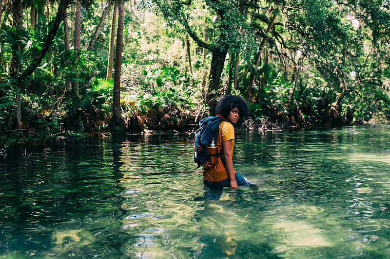 person in orange top wearing backpack walking on body of water in forest during daytime, HD wallpaper